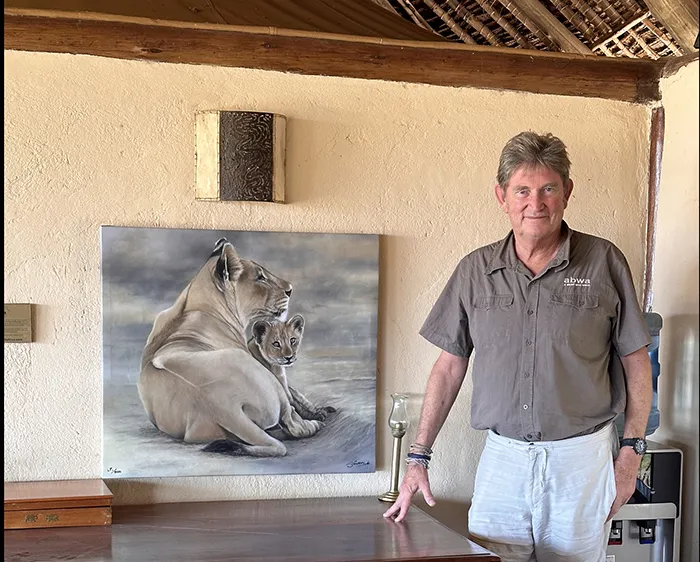 Simon stands next to a canvas of a Lioness and her cub titled 'Mini Me'